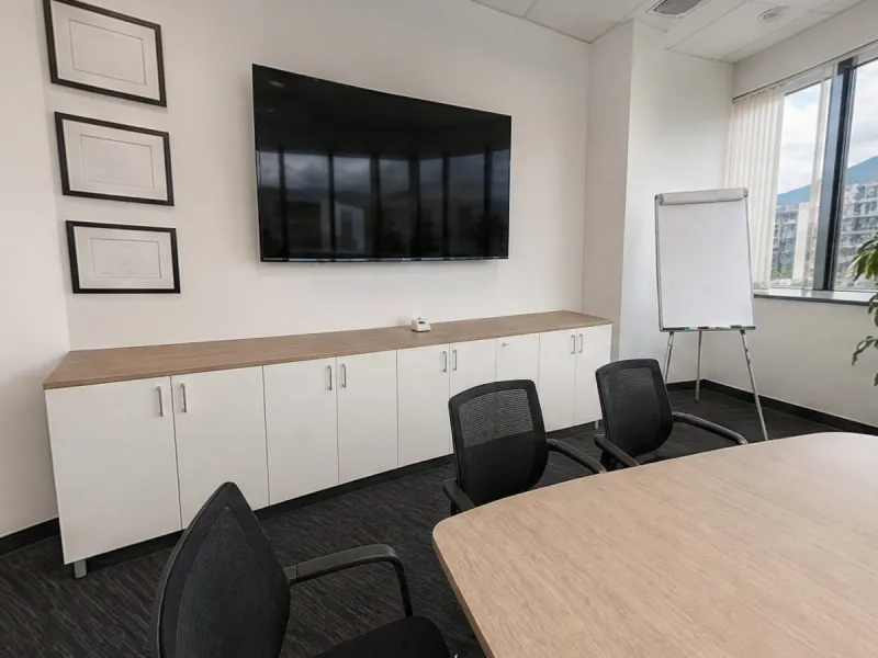 A meeting room rebuilt as an escape room scene from phone photos: TV wall, framed certificates and a long table