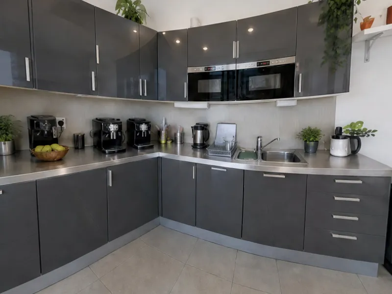 The office kitchen as a game scene: dark grey cabinets, coffee machines and a clean steel counter